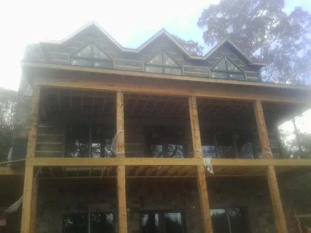 Dormers and porch framing on a large log home under construction — Roof Coating work by our crew in Medford